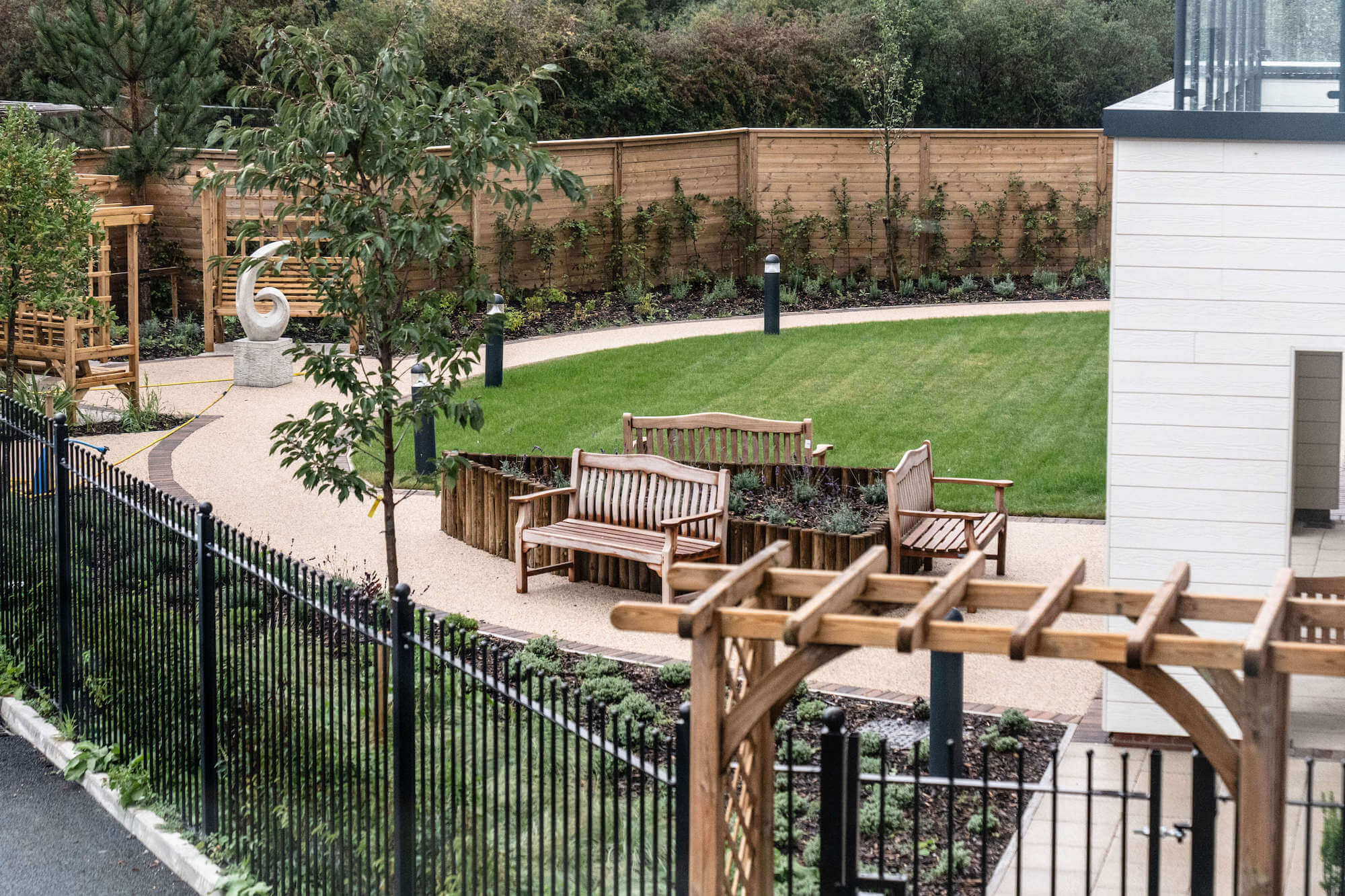 A view of the landscaped garden with benches and a pergola at Alexandra Mill Care Home.