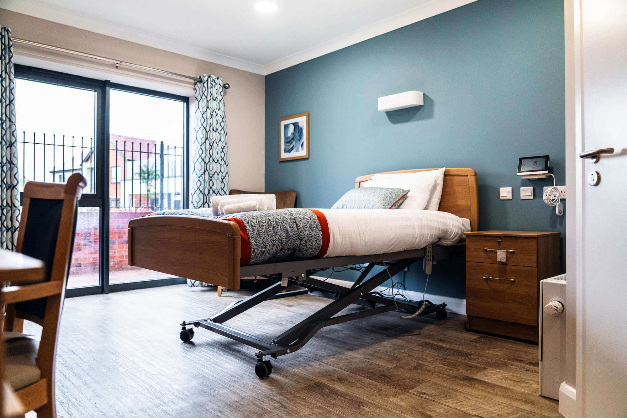 Raised and dressed bed in a standard bedroom at Alexandra Mill Care Home.