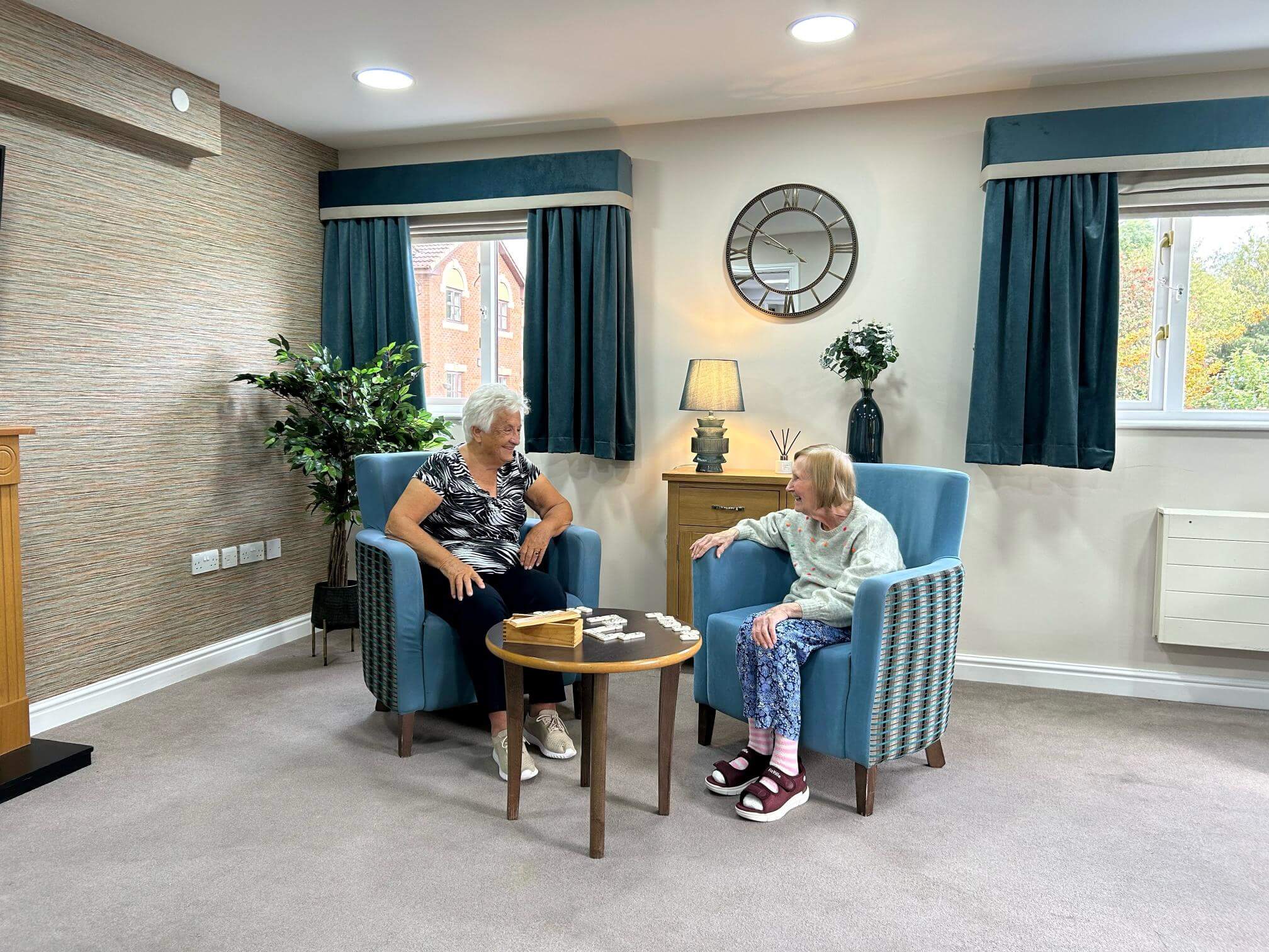 Residents relaxing and chatting sitting in the Chailey lounge.