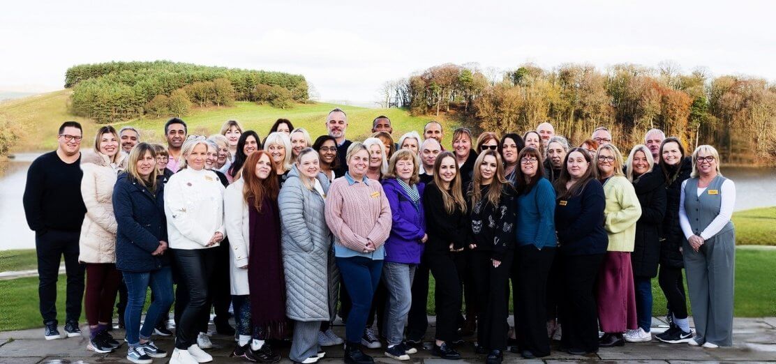 Group photo of people who work at Anavo in front of Lake Coniston.